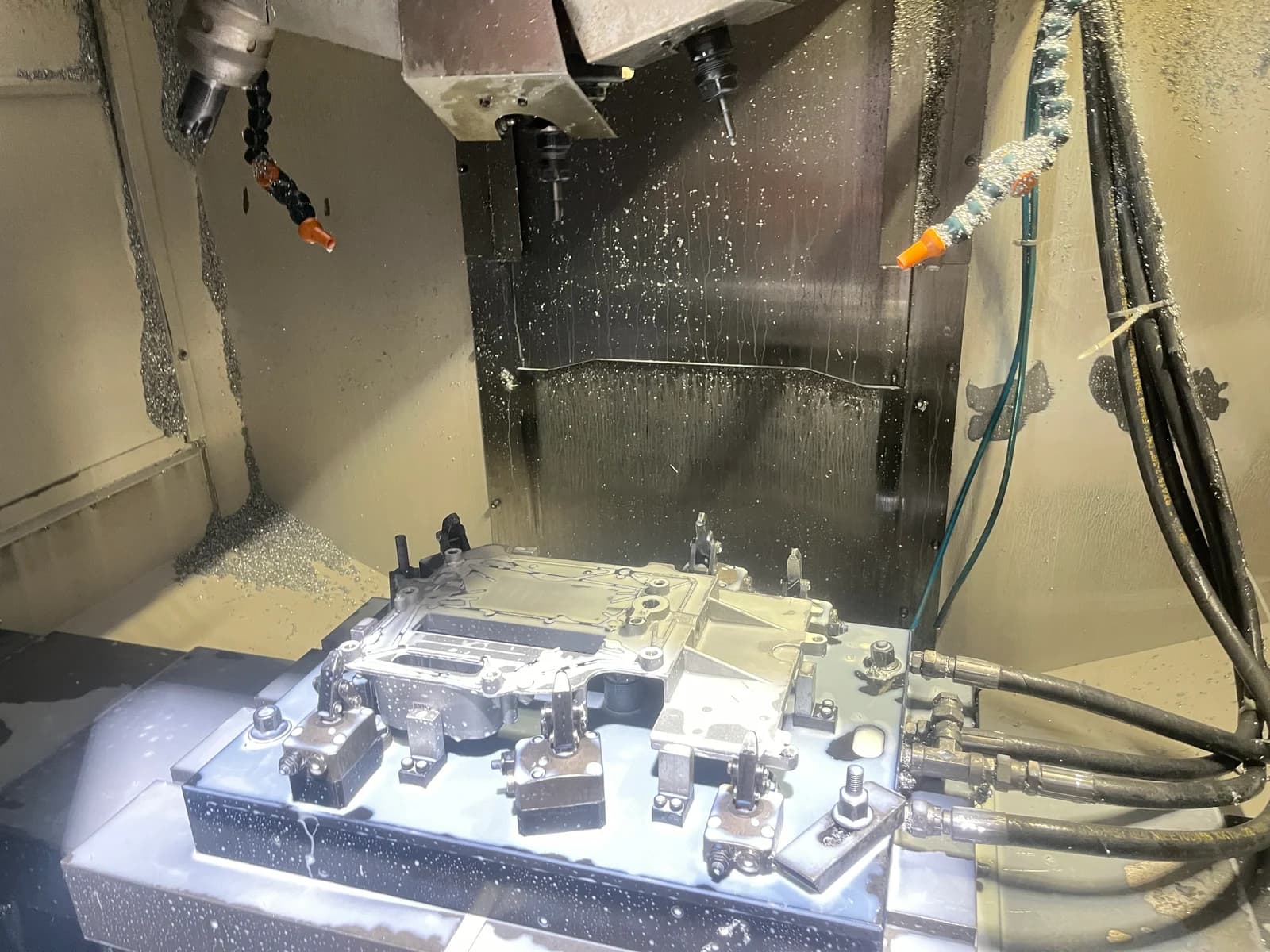 A workpiece held in a CNC machining fixture with tooling above