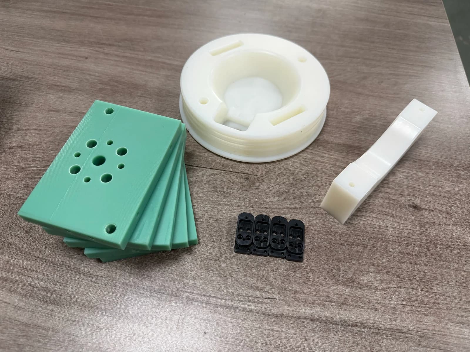 Green plates with hole patterns, a white round housing, a white bracket and small black parts
