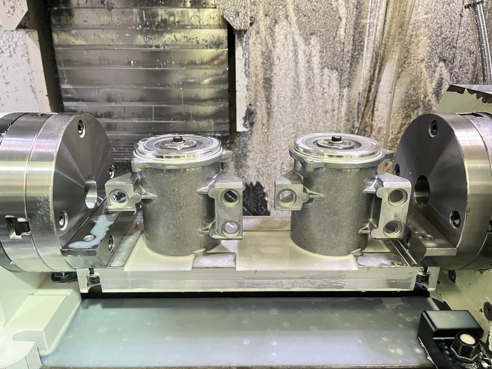 Two workpieces mounted between rotary fixtures inside a machining center
