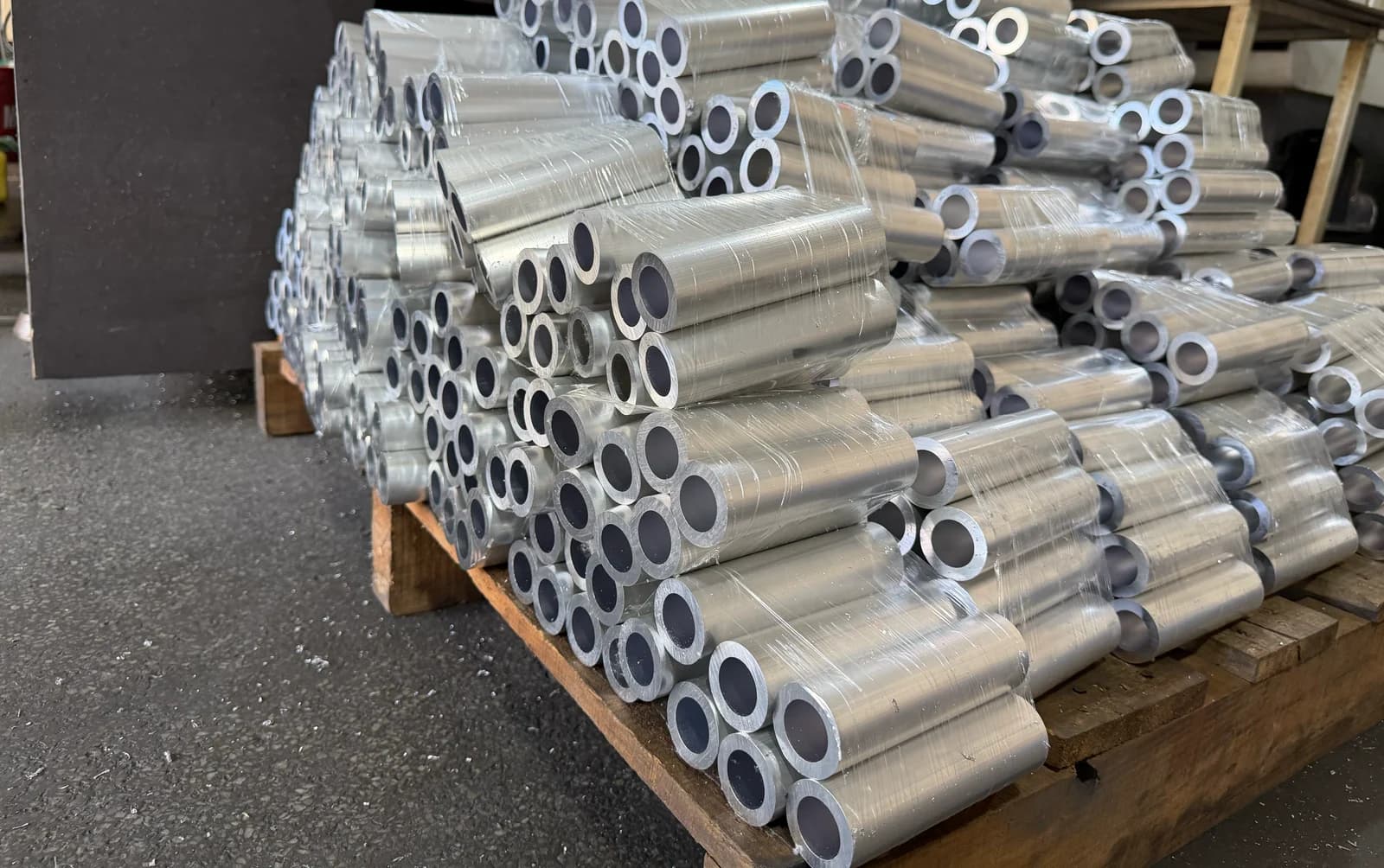 Bundles of metal tube sections wrapped in film on a wooden pallet